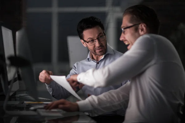 Boss and employee discussing papers at night meeting