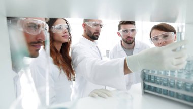 arka plan görüntüsü sıvı cam tüp içinde eğitim microbiologists oluşan bir gruptur.