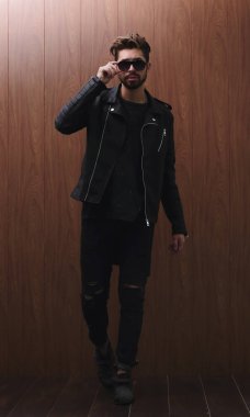 Siyah deri ceketli ve kot pantolonlu bir adam