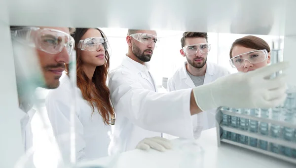 Immagine di sfondo è un gruppo di microbiologi che studiano il liquido nel tubo di vetro . — Foto Stock