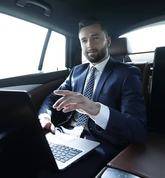 Geschäftsmann sitzt im Auto auf dem Rücksitz und zeigt mit dem Finger nach vorne — Stockfoto