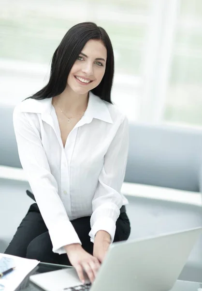 Successful young woman sitting at a desk on a blurred background. Stock Image