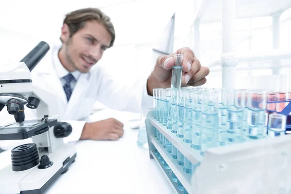Химик смотрит на пробирки с голубыми жидкостями Лицензионные Стоковые Изображения