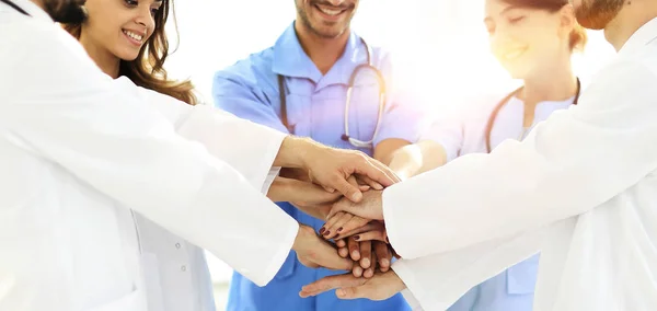 Artsen en verpleegsters stapelen handen op. concept van wederzijdse bijstand. — Stockfoto
