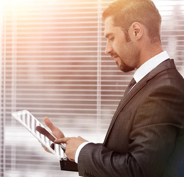 Closeup.businessman con el ordenador tableta de pie junto a la ventana . —  Fotos de Stock