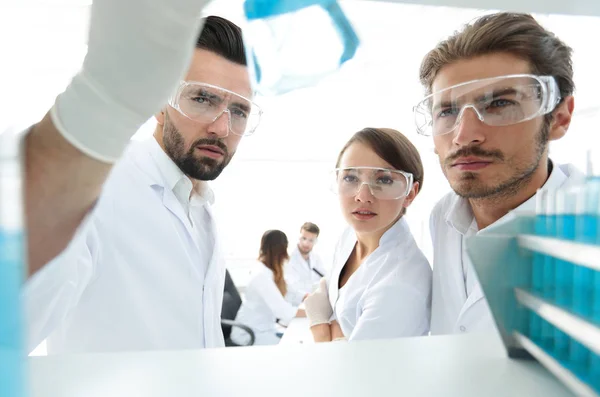 Fechar. cientista e assistente estudando a solução no tubo de vidro — Fotografia de Stock