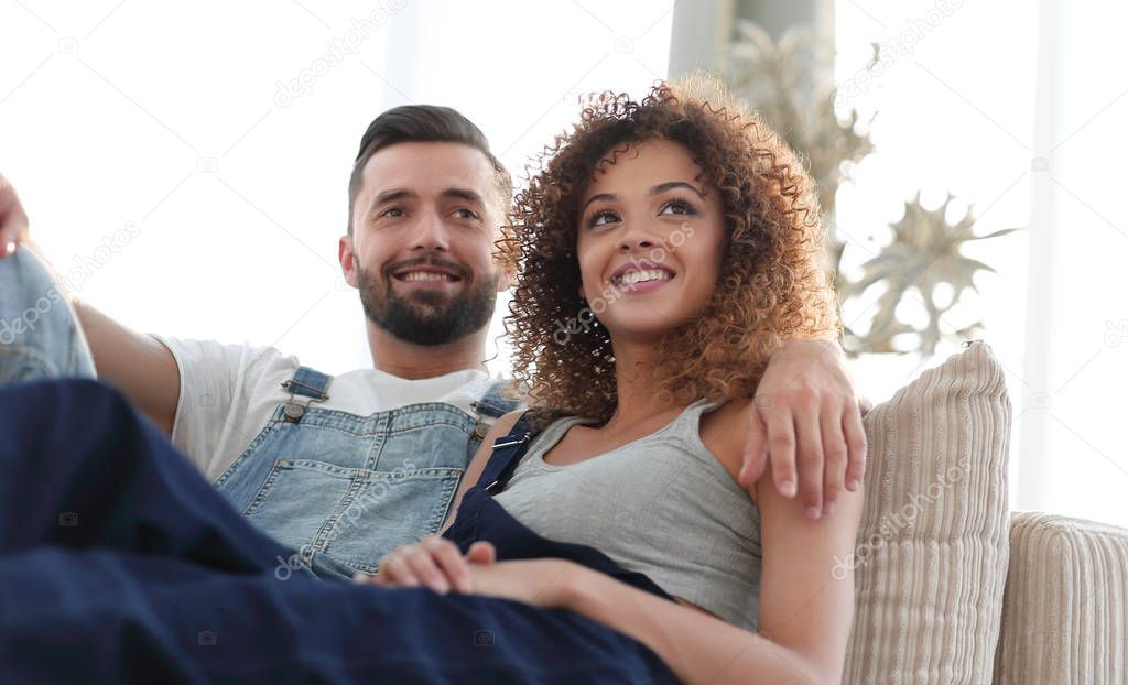 Young couple in work clothes sitting on couch