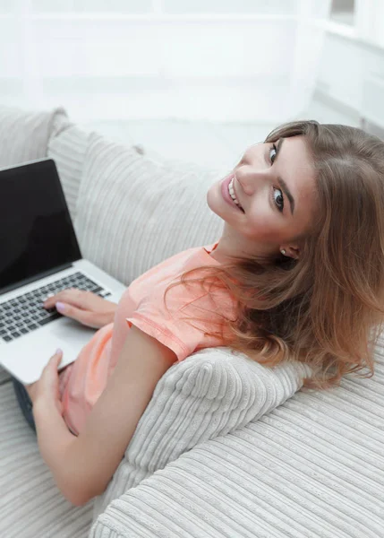 Портрет молодой женщины, работающей с ноутбуком сидя на диване — стоковое фото