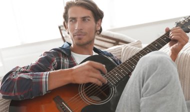 oturma odasında kanepede oturup gitar ile Modern adam.