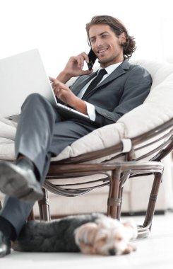 onun evinde sandalyede oturan smartphone cep telefonu ile konuşurken işadamı