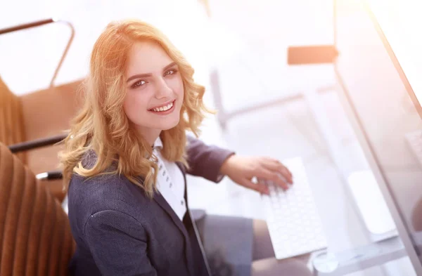 Glimlachende zakenvrouw zitten achter een bureau — Stockfoto