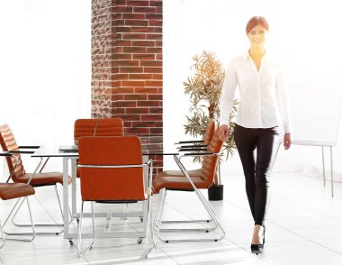 Gülümseyen genç bayan asistan ofiste dolaşıyor..