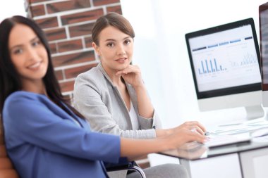 Kameraya bakarak ve oturma işyerinde gülümseyen genç kadın