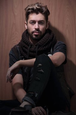 Sıradan giyinmiş sakallı bir adam oturur.