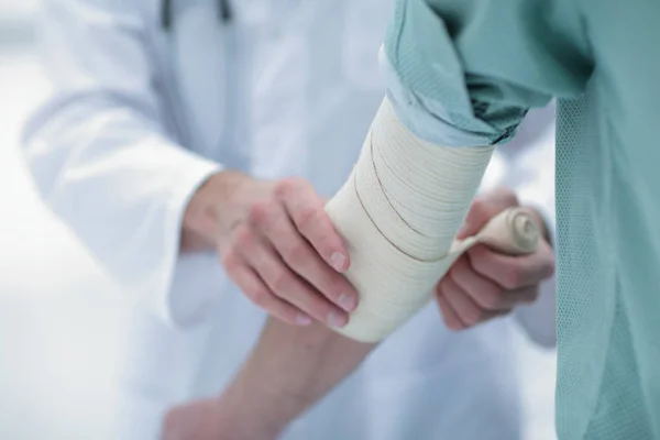 Médico que aplica vendaje elástico en el codo del paciente . — Foto de Stock