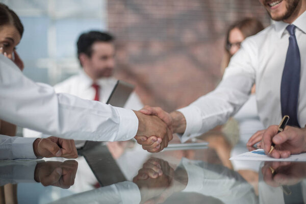 рукопожатие бизнес-партнеров на фоне рабочего стола
