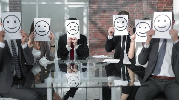 Equipo de negocios con iconos sonrientes sentado en el escritorio —  Fotos de Stock