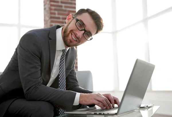 Jonge zakenman met behulp van laptop en glimlachen — Stockfoto