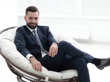 Kendine güvenen işadamı bir sandalyede oturuyor