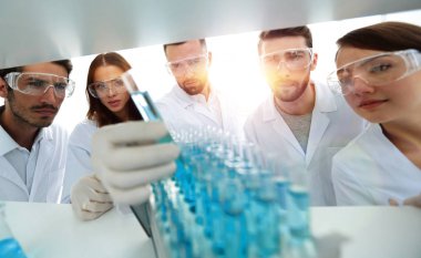 arka plan görüntüsü sıvı cam tüp içinde eğitim microbiologists oluşan bir gruptur.