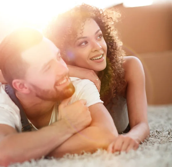 Happy couple lying on the carpet on the blurred background — Stock Photo, Image