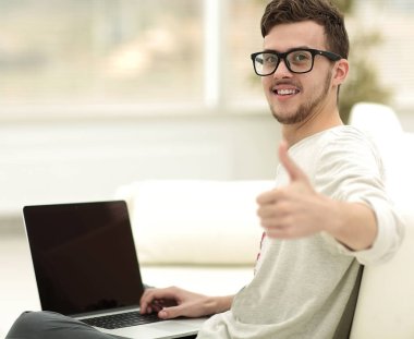 açık belgili tanımlık laptop önünde oturan ve gösterilen modern genç yukarı başparmak