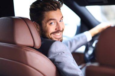 Dikiz aynası, genç adam arabasını sürüyor, kameraya bakıyor.