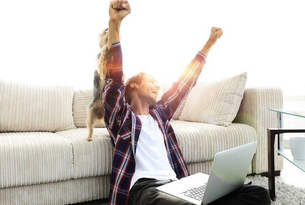 Mutlu adam oturma odasındaki kanepenin yanında köpeğiyle seviniyor..