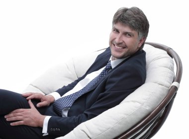 yan görünümü. Rahat koltuk kameraya bakarak oturan işadamı