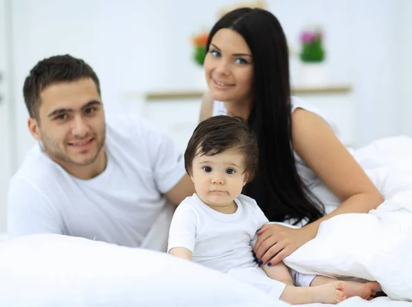 Familia alegre divirtiéndose juntos acostados en una cama — Foto de Stock