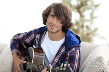 modern adam kanepede oturan gitar çalmak. bir yaşam tarzı kavramı