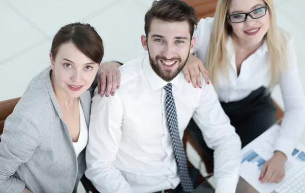 Succesvolle business team zitten aan tafel en kijken naar camera. — Stockfoto