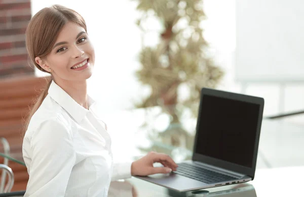 Jovem mulher de negócios sentada em sua mesa em um escritório, trabalhando em um computador portátil — Fotografia de Stock