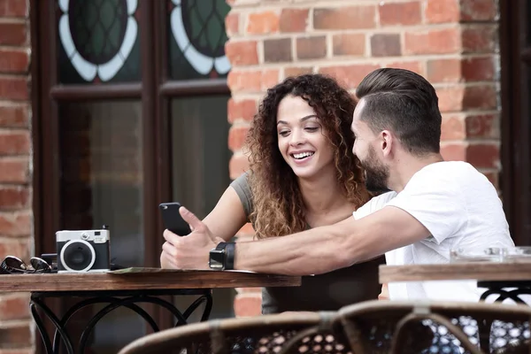 Porträt eines jungen Paares, das sich auf eine Caféterrasse setzt — Stockfoto