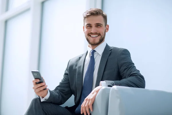 Affärsman sitter i en fåtölj med telefon — Stockfoto