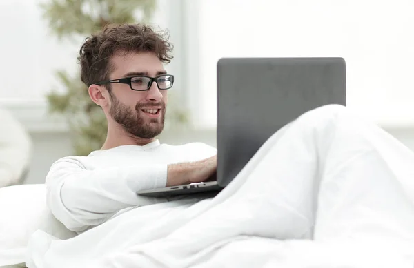 Hombre guapo trabajando en portátil acostado en la cama — Foto de Stock