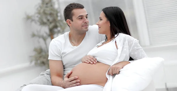 Husband and pregnant wife lying on the bed in the bedroom. — Stock Photo, Image