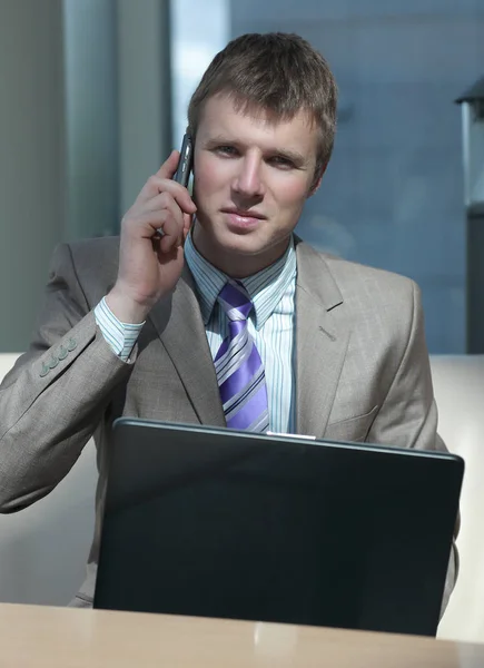 Atractivo tipo europeo hablando por teléfono mientras usa el ordenador portátil . — Foto de Stock