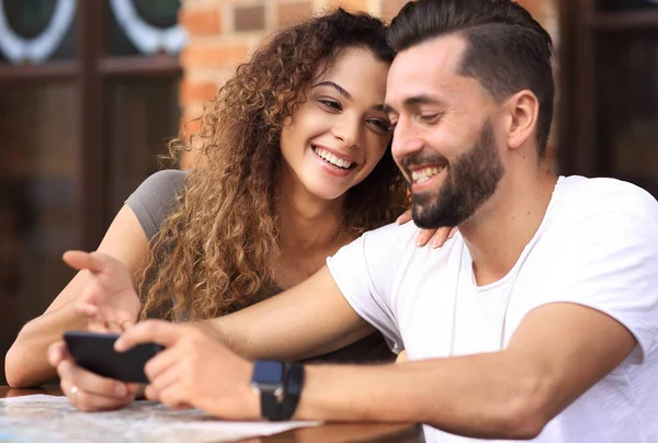 Feliz pareja amorosa usando un teléfono inteligente sentado en la terraza — Foto de Stock