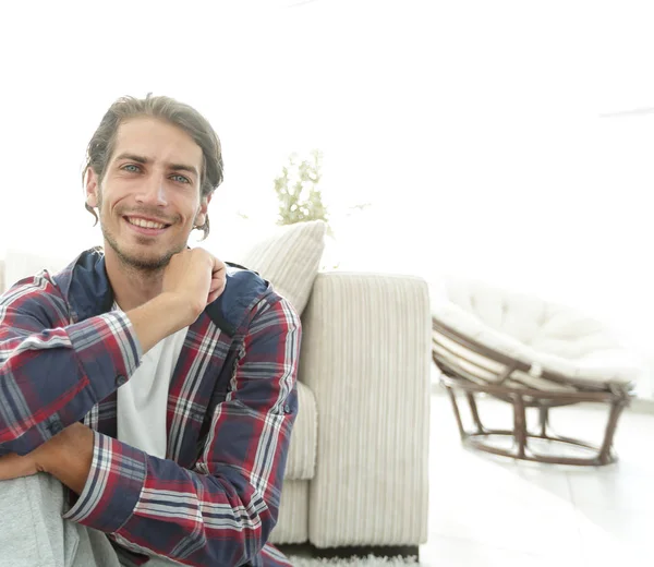 Ευτυχισμένος τύπος που κάθεται στο χαλί σε ένα νέο διαμέρισμα. — Φωτογραφία Αρχείου