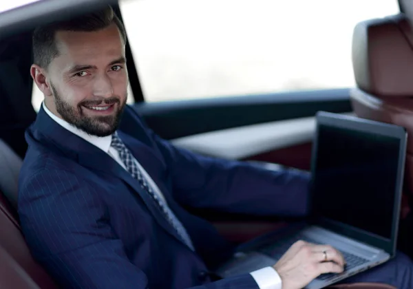 Primo piano di un uomo d'affari con un portatile seduto in macchina — Foto Stock