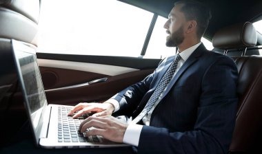 Arabanın içinde otururken dizüstü bilgisayarda metin yazarak işadamı