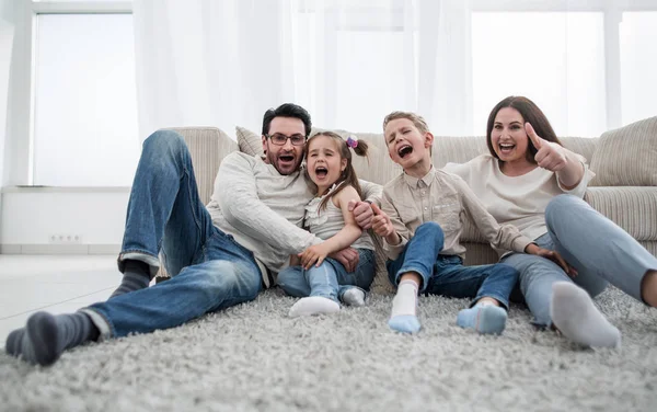 Счастливая семья, сидящая на ковре в гостиной — стоковое фото
