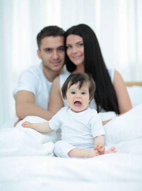 yatakta evde oturan neşeli bir aile portresi