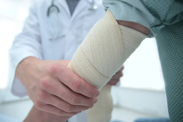 Ortopedista aplicando bandagem nos pacientes mão na clínica — Fotografia de Stock