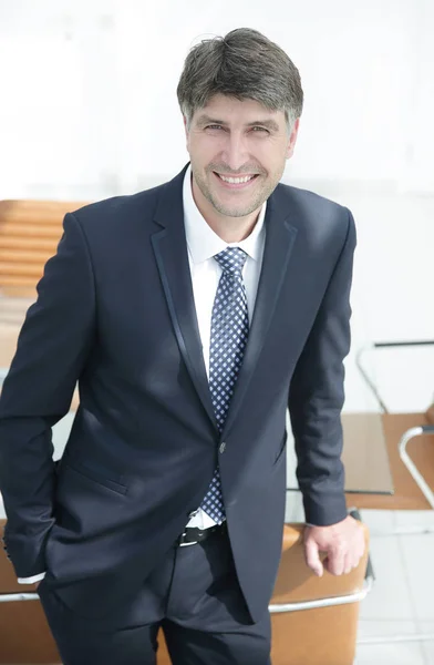 Hombre de negocios serio de pie cerca del lugar de trabajo en la oficina . —  Fotos de Stock