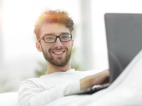 Smiling man using laptop lying on bed — Stock Photo, Image