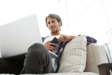 fotoğraf genç adam ile smartphone bir sandalyede oturuyor. bulanık bir arka plan üzerinde