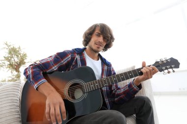 adam bir şarkı söyler ve kanepede oturan gitar çalar.