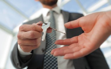 Emlakçının ofisteki adama evin anahtarlarını verirken çekilmiş görüntüsü.